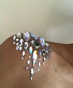 A close up of Alexandrina's bare shoulder, jewelled with teardrop clear gem stones. Against a white background